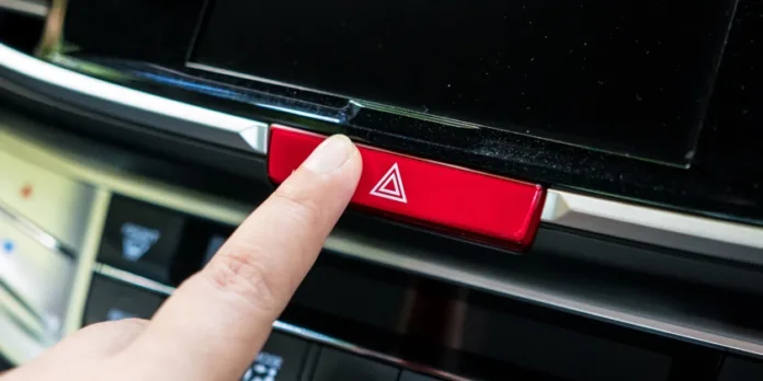 finger pressing the car emergency button on car's dashboard, inside car. lampu hazard